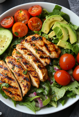 Grilled chicken salad bowl with avocado, cherry tomatoes, cucumber, and mixed greens.