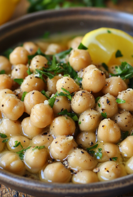 Bowl of chickpeas with lemon wedge, parsley, olive oil, and black pepper.