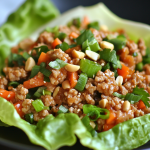 Close-up of Asian turkey lettuce cups with ground turkey, chopped carrots, green onions, and peanuts served in crisp butter lettuce leaves