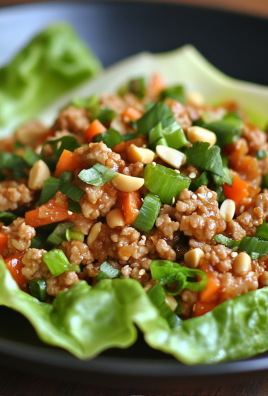 Close-up of Asian turkey lettuce cups with ground turkey, chopped carrots, green onions, and peanuts served in crisp butter lettuce leaves