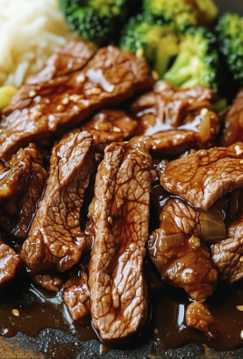 Close-up of juicy beef slices glazed in savory brown sauce, served with steamed broccoli and rice.